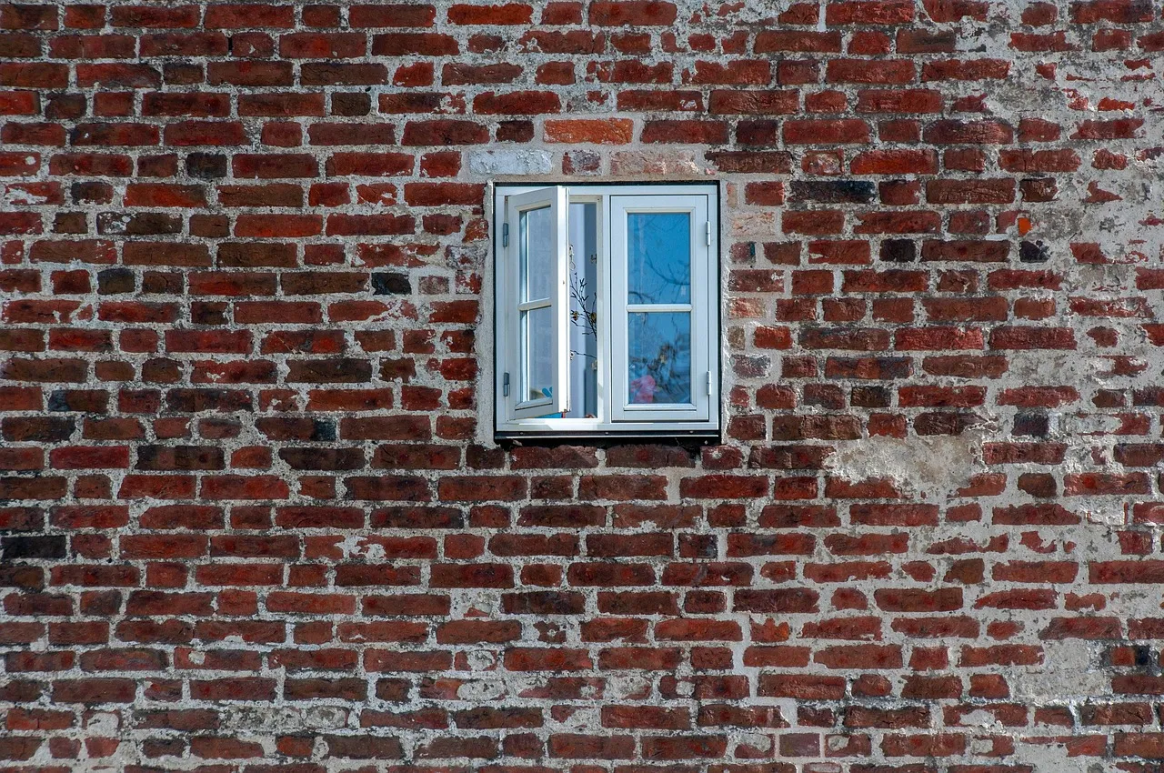 Facade af røde mursten med et lille hvidt vindue og slidte fuger